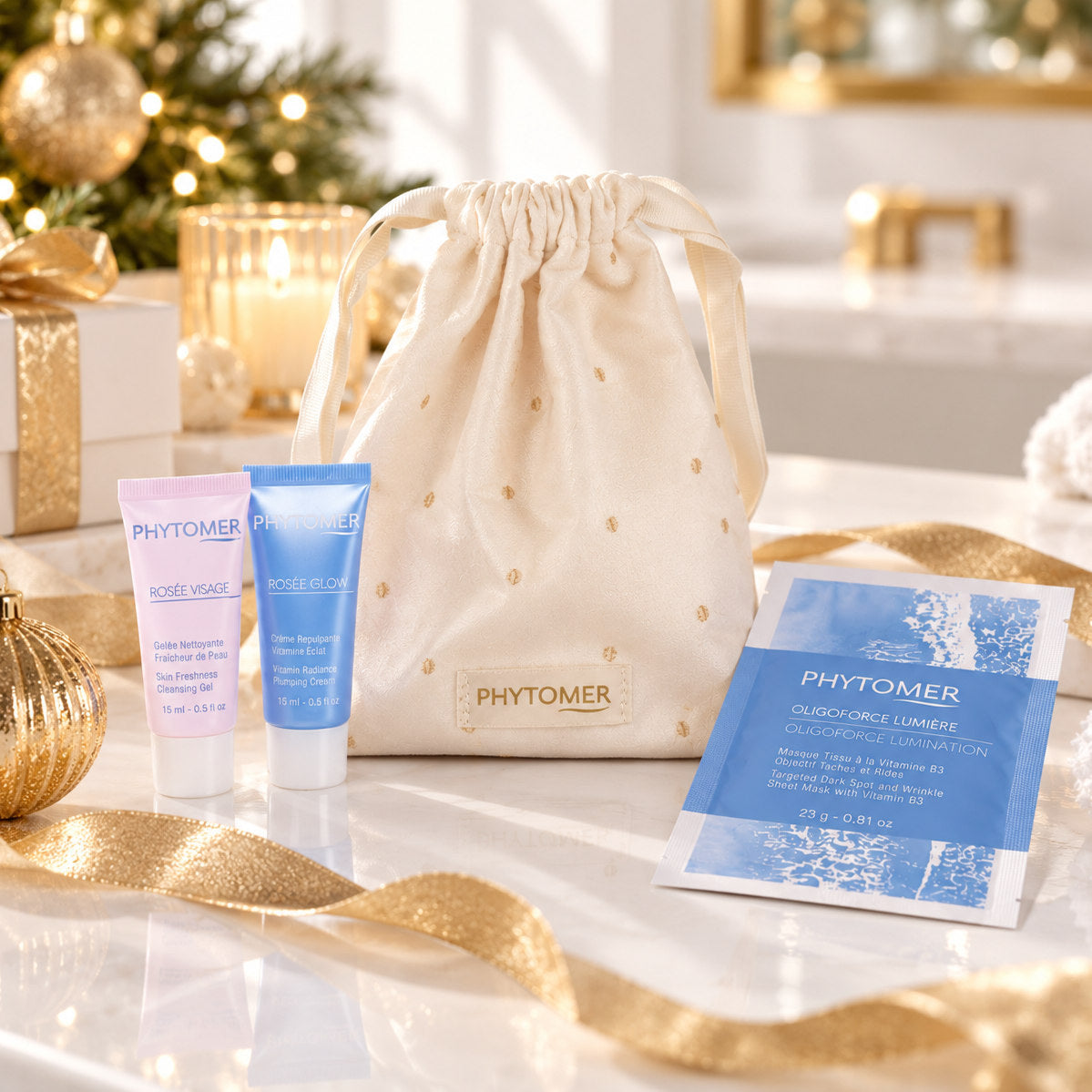 PHYTOMER Ritual Glow Christmas gift set with ivory pouch, Rosée Visage and Rosée Glow mini tubes and Oligoforce Lumière sheet mask in festive setting.