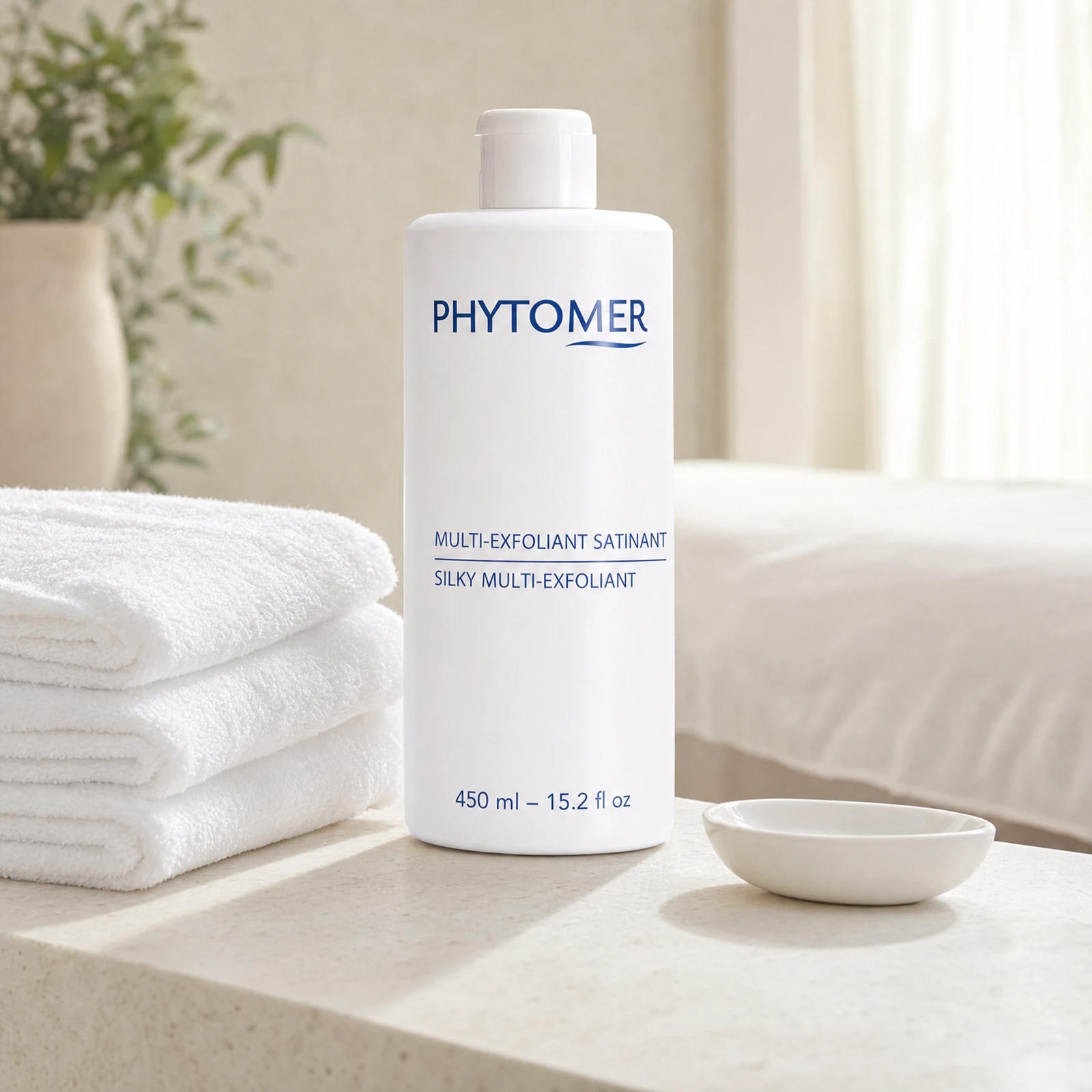 Phytomer Silky Multi-Exfoliant 450ml professional bottle on a premium spa body treatment counter with white towels and ceramic dish