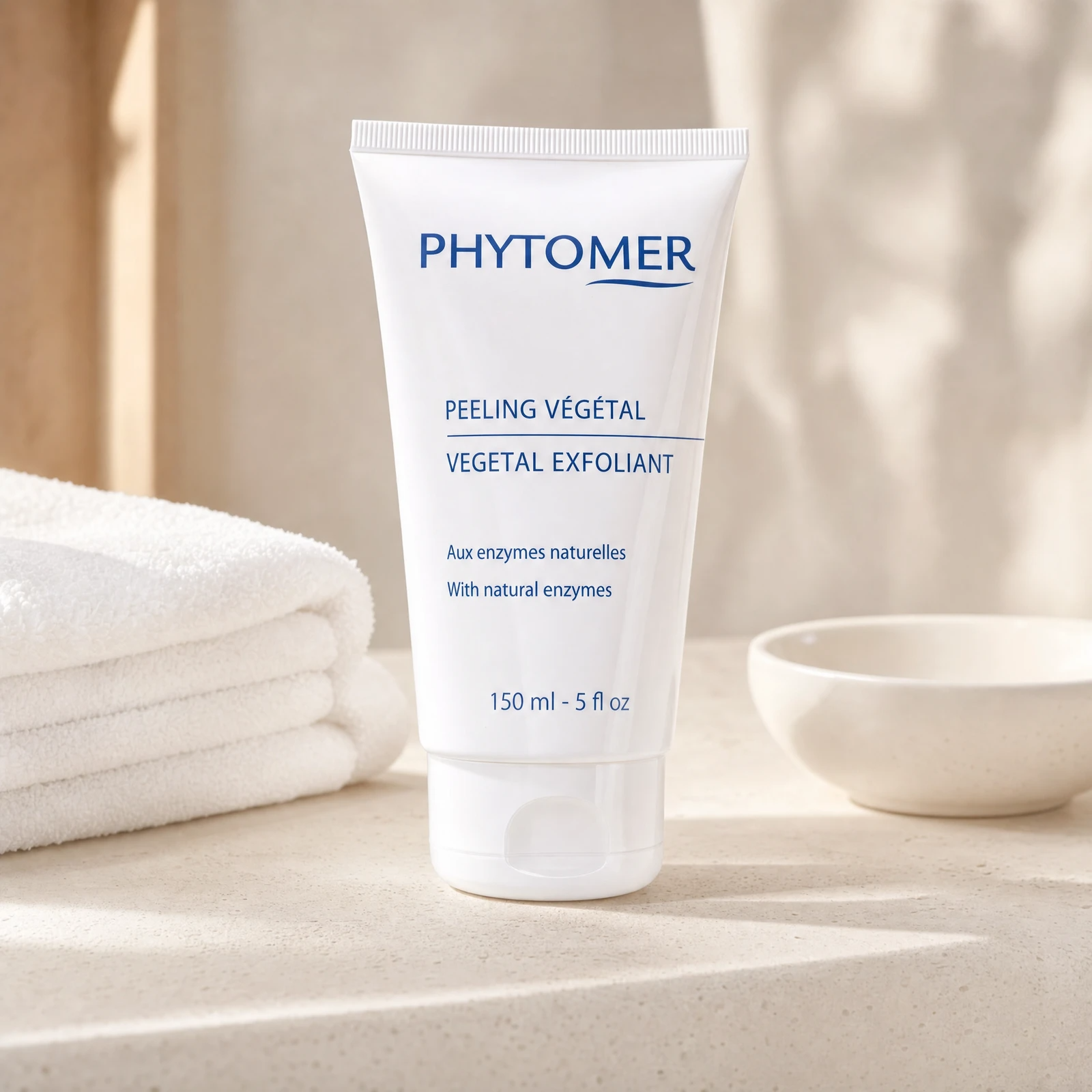 Phytomer Vegetal Exfoliant with Natural Enzymes 150ml professional tube on a premium beauty clinic warm-stone counter with white spa towels and ceramic dish
