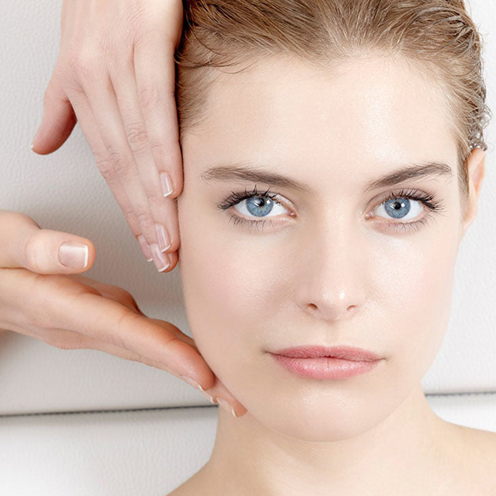 Woman with clear skin and hand gently touching her face.