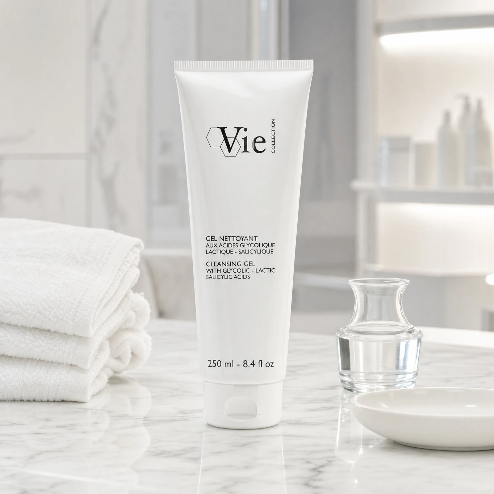 Vie Collection Cleansing Gel with Glycolic Lactic Salicylic Acids 250ml on a white marble spa treatment counter with stacked white spa towels, glass carafe with water, white ceramic dish and illuminated clinical product shelf in background, professional clinic setting